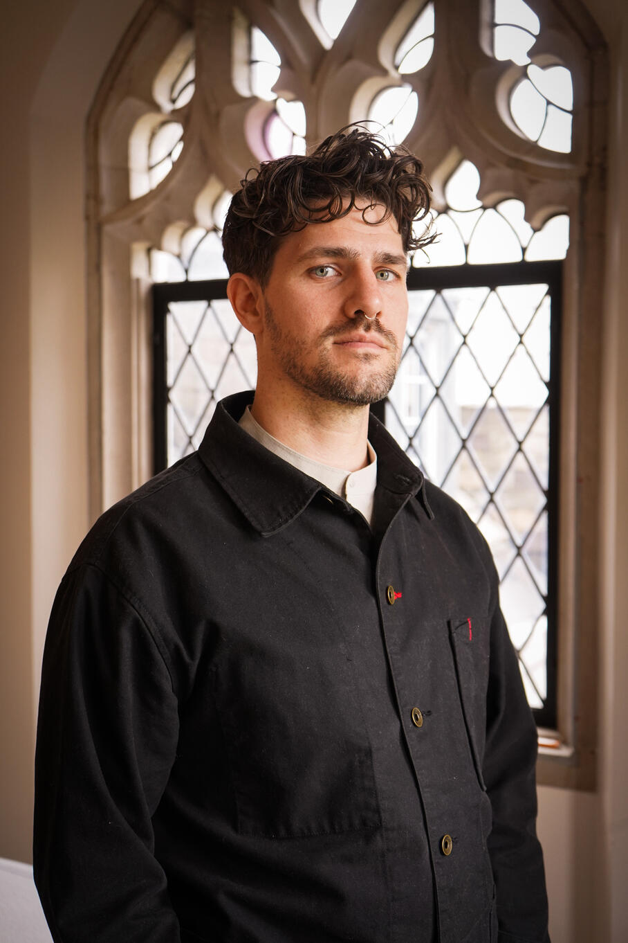 Therapist and educator, Kyle Sullivan, standing in a spacious therapy office near Highland Park in front of large windows.